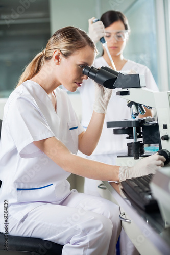 Scientist Looking Into Microscope In Lab