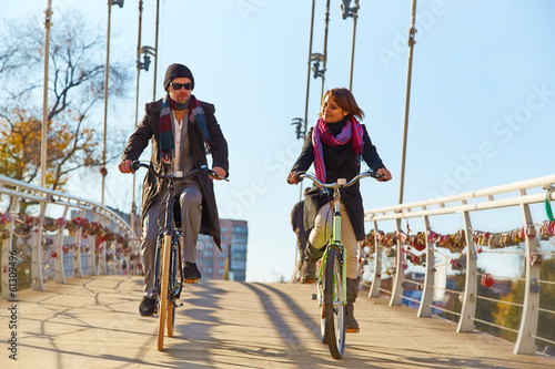 Young couple riding a bicycle across the bridge
