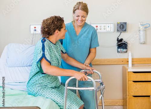 Nurse Assisting Patient Using Walking Frame In Hospital photo