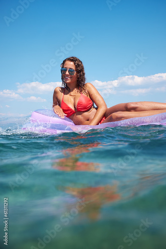 very happy woman on pink air bed in sea © ZoomTeam