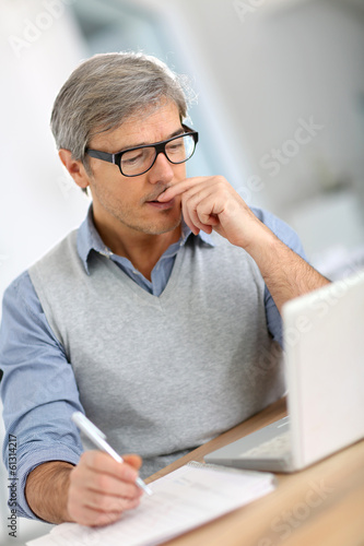 Senior businessman in office working on laptop