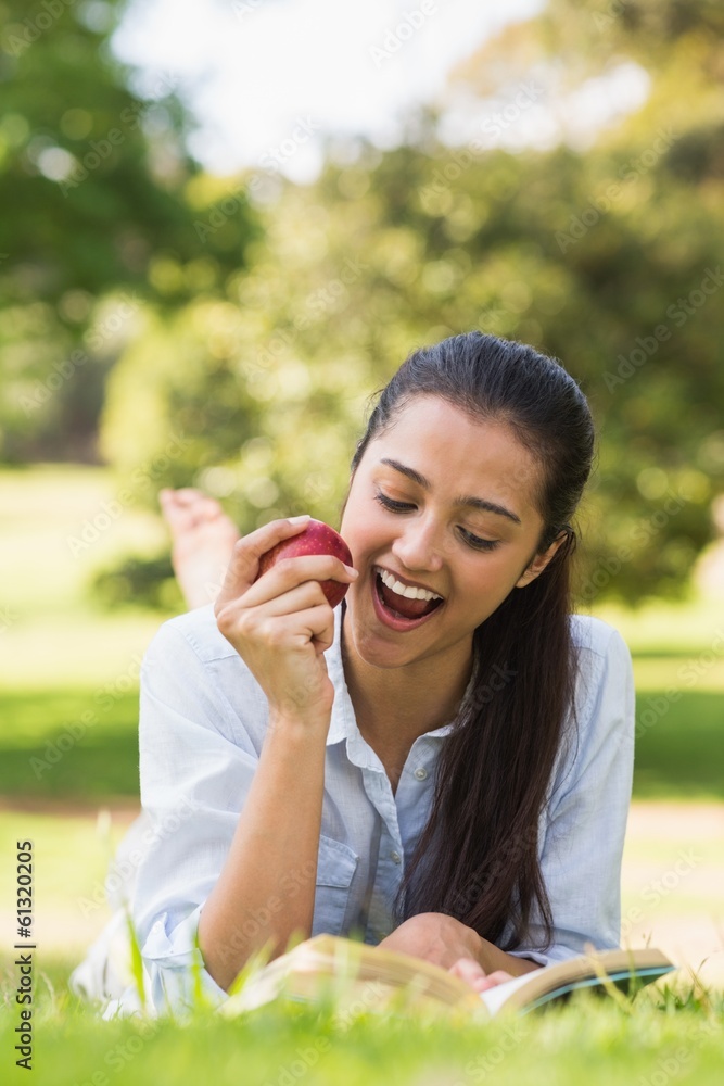 Woman eating apple while reading a book in park Woman eating apple while reading a book in park