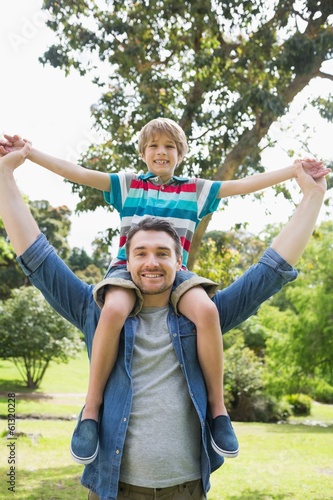 Father carrying boy on shoulders in park