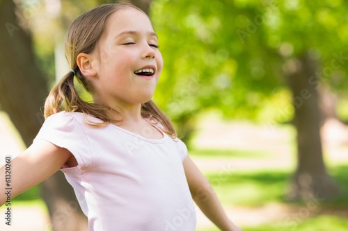 Girl with arms outstretched and eyes closed at park