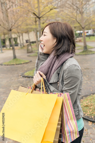 Asian woman talk on phone hold shopping bags