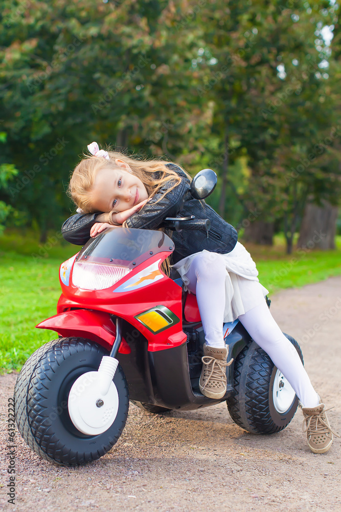 Beautiful little girl having fun on her toy motorcycle