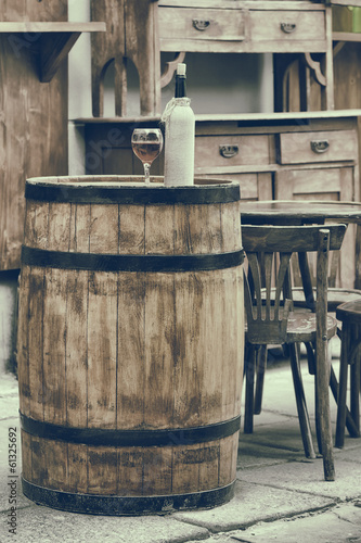 Vintage stylized photo of wooden barrel with bottles of wine and
