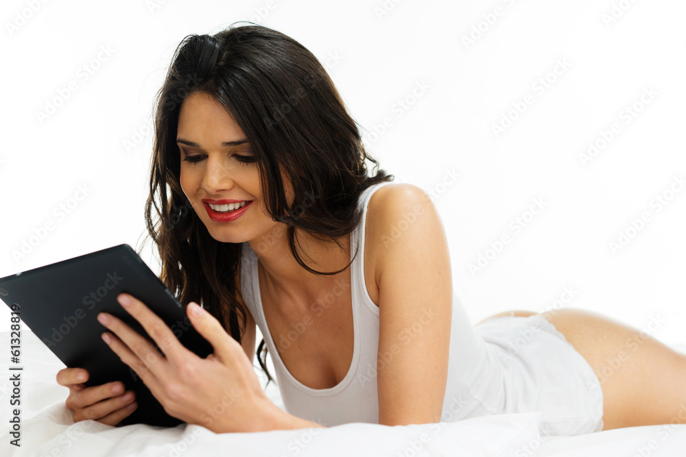 Young woman reading a tablet on the bed Young woman reading a tablet on the bed