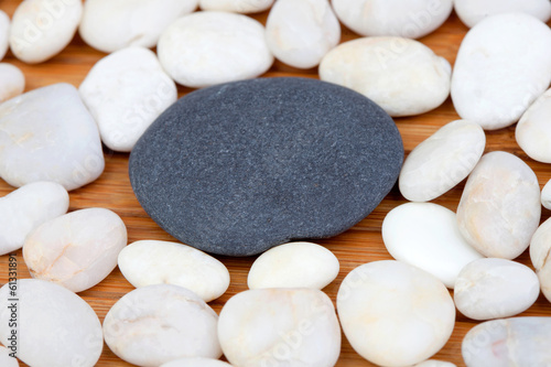 Canvas Print A black stone and many small white stones