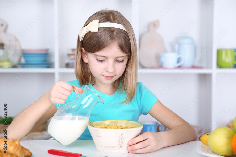 Beautiful little girl eating breakfast in kitchen at home Beautiful little girl eating breakfast in kitchen at home