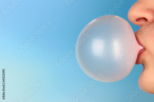 Person doing bubble with chewing gum on bright background photo