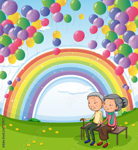 An old couple below the floating balloons and the rainbow
