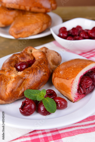 Fresh baked pasties with cherry on plate on table close-up