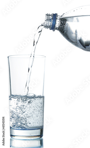 Pour water from bottle into glass, isolated on white