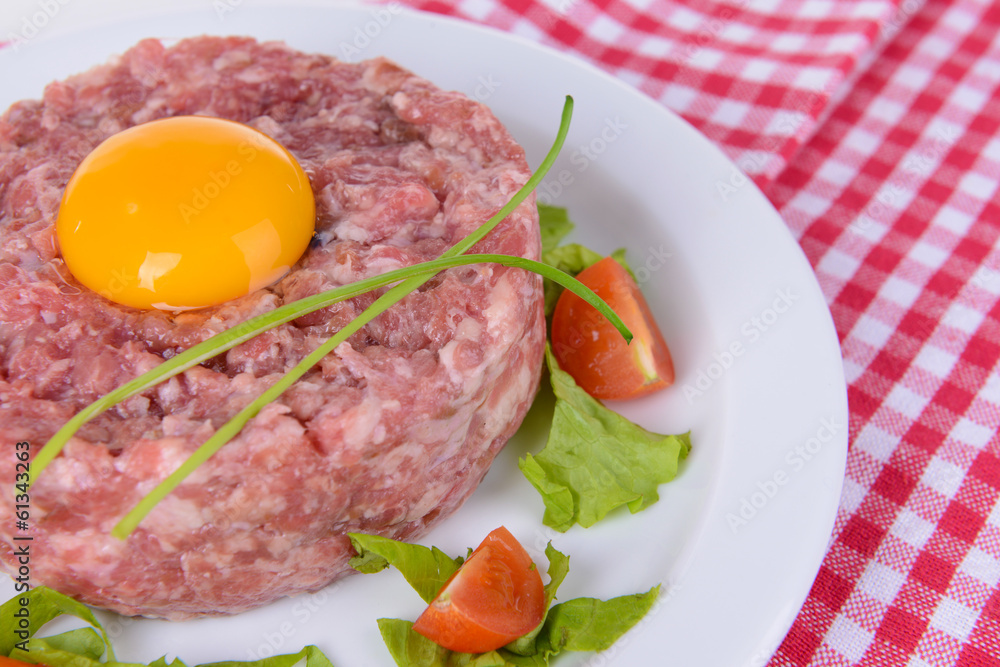 Delicious steak tartare with yolk on plate on table close-up Delicious steak tartare with yolk on plate on table close-up