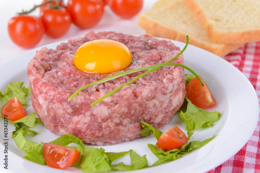 Delicious steak tartare with yolk on plate on table close-up Delicious steak tartare with yolk on plate on table close-up