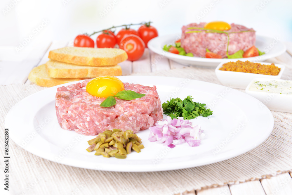 Delicious steak tartare with yolk on plate on table close-up Delicious steak tartare with yolk on plate on table close-up