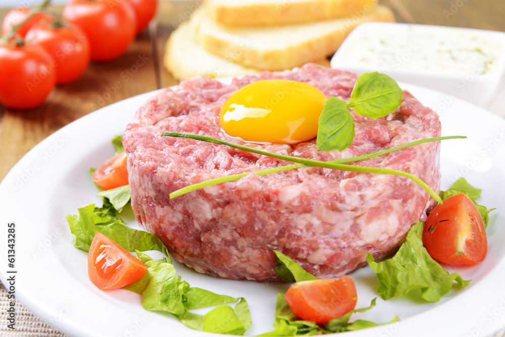 Delicious steak tartare with yolk on plate on table close-up Delicious steak tartare with yolk on plate on table close-up