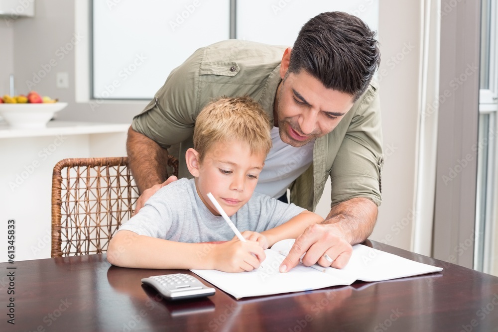 Happy father helping son with math homework at table Happy father helping son with math homework at table