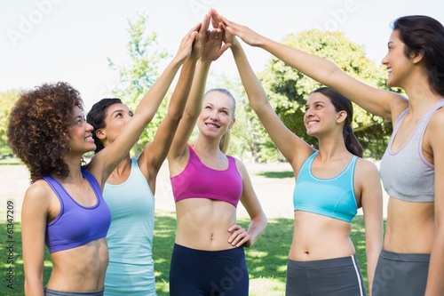 Women in sportswear raising hands in park