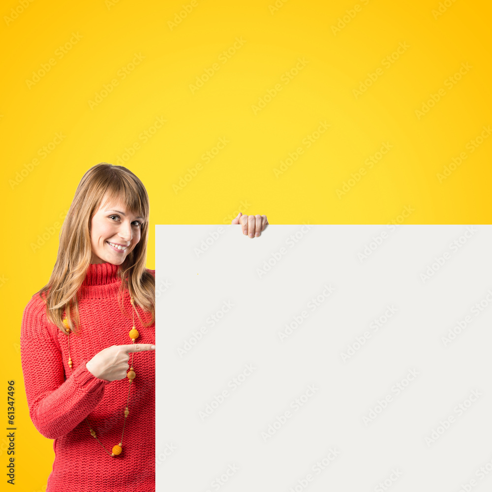Young blonde girl holding placard over yellow background Young blonde girl holding placard over yellow background