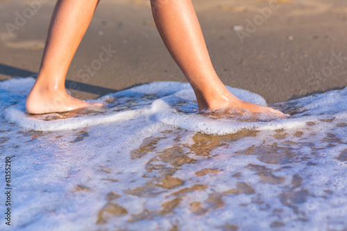 Child walking with bare feet along the seashore © len44ik