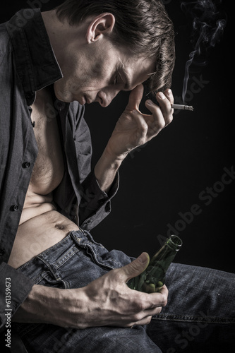 Lost everything. Depressed man smoking and drinking alcohol
