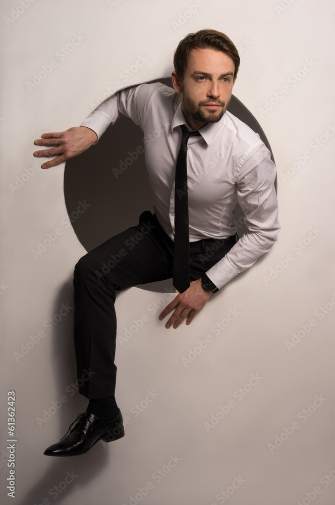 Businessman climbing out of a circular hole Businessman climbing out of a circular hole