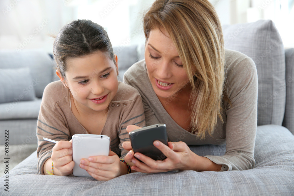 Mother and daughter playing games with smartphone Mother and daughter playing games with smartphone