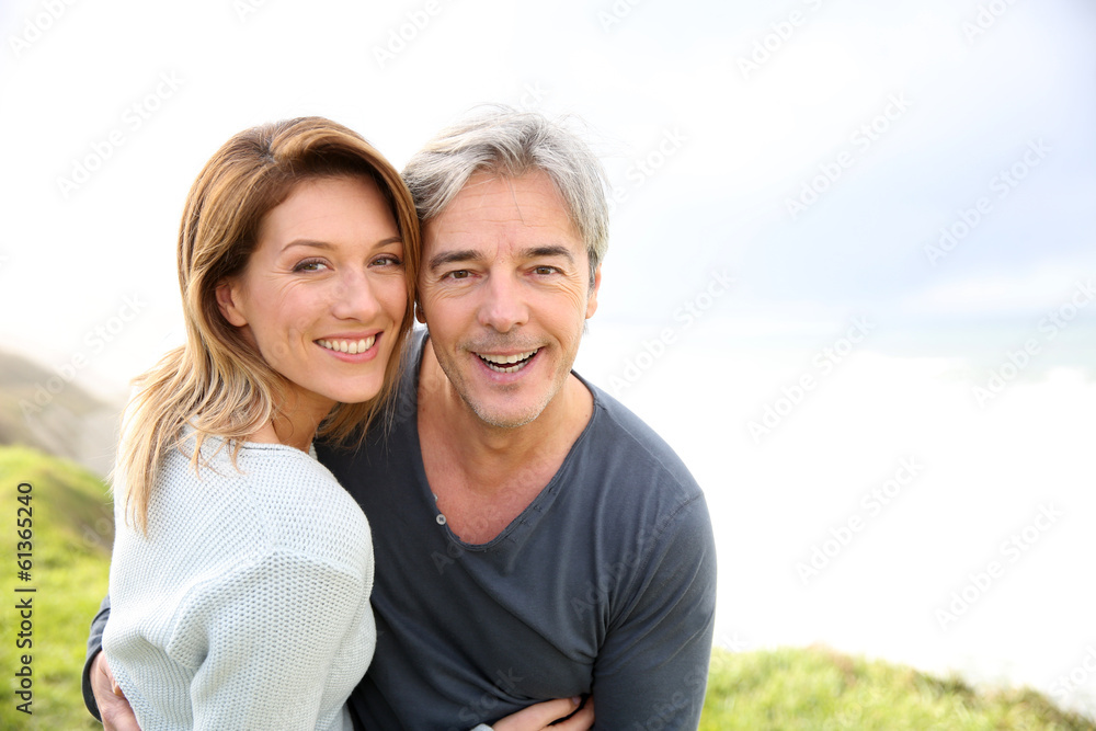 Cheerful middle-aged couple on the ocean coastline Cheerful middle-aged couple on the ocean coastline