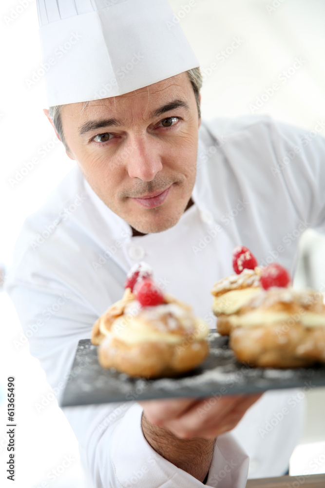 Chef holding plate of pastries towards camera