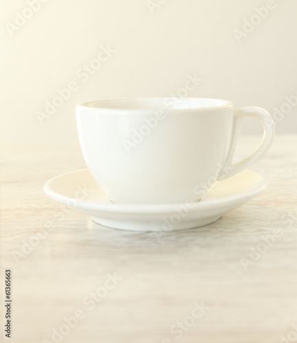 A white teacup on a wooden table © Fxquadro