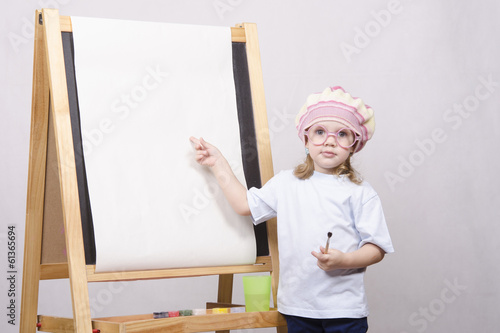 Девочка художник в очках рисует на мольберте