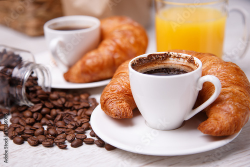 Two cups of coffee with croissants and a cup of orange juice