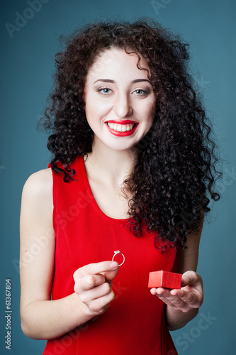 Smiling girl getting out a ring from a red gift box