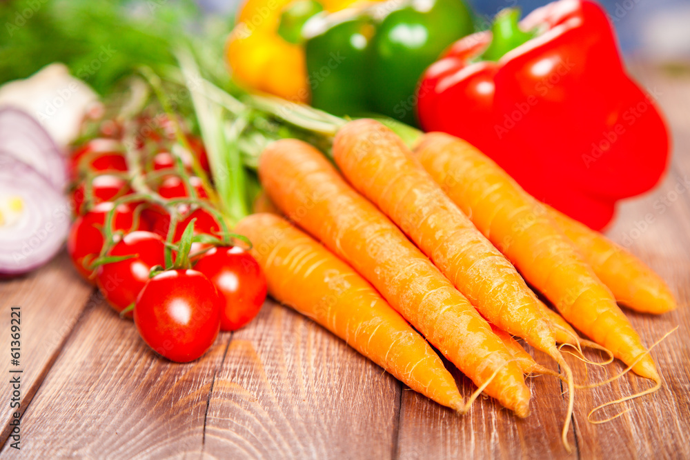 Carrot, tomato and paprika on a wooden table