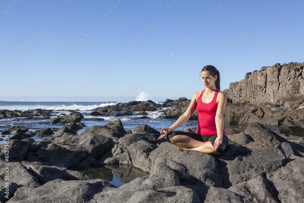 young woman practicing yoga meditation on the beach