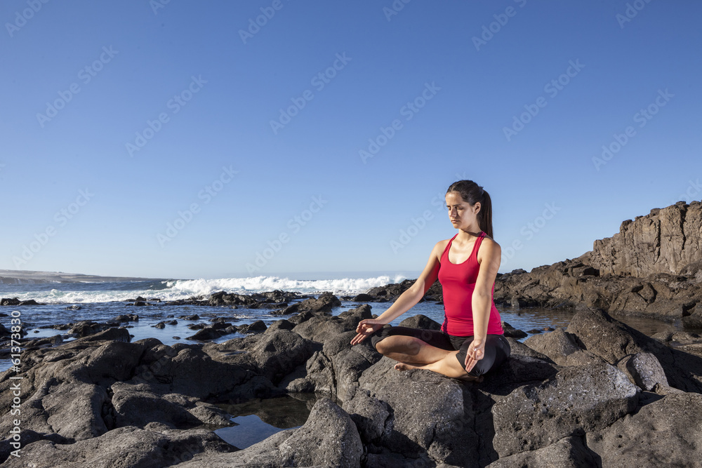 young woman practicing yoga meditation on the beach