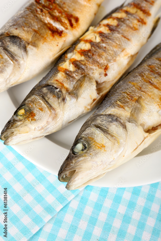 Delicious grilled fish on plate on table close-up Delicious grilled fish on plate on table close-up