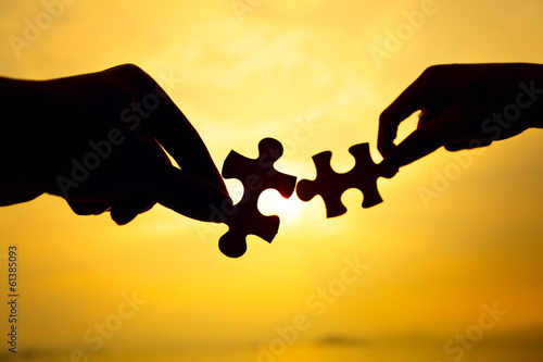 Silhouette of two hands connect puzzle together