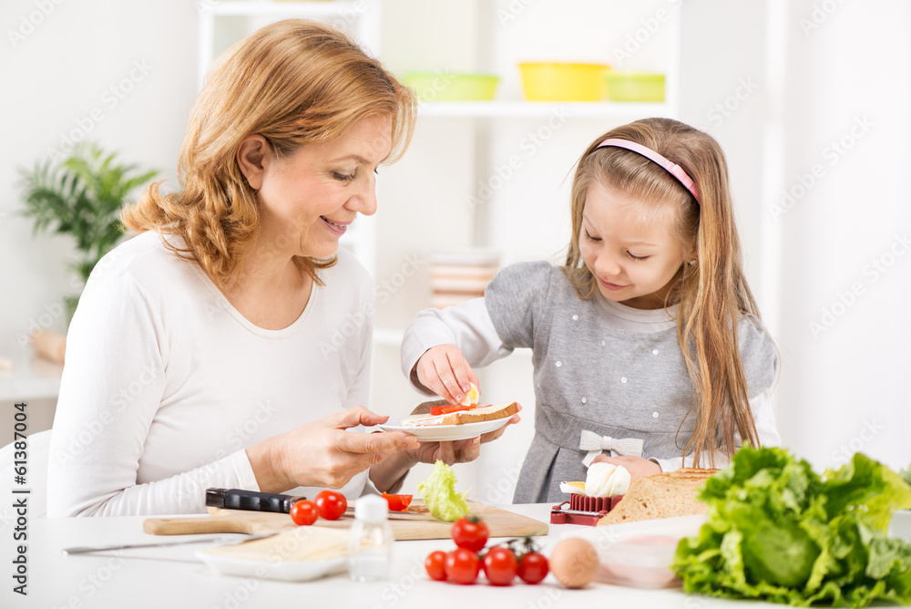 Cute little girl with Grandmother making a Sandwich.
