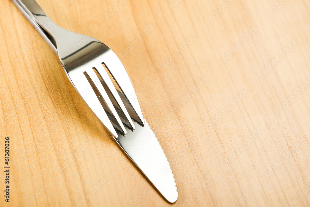 Knife and fork on wooden table Knife and fork on wooden table