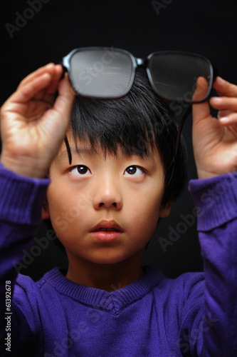 Asian boy with bad eyesight trying his new glasses photo