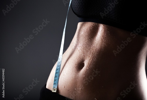 Woman sporty belly after exercise with measuring tape