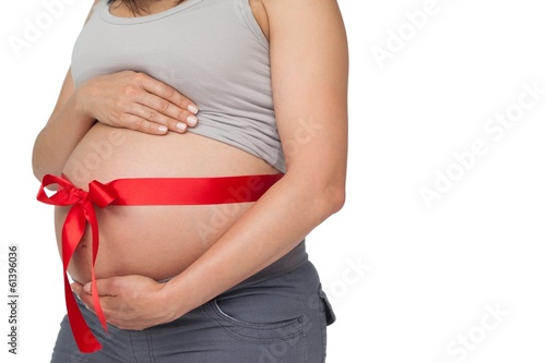 Pregnant woman with a red bow around her bump © WavebreakMediaMicro
