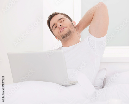 handsome man sitting in bed and working.