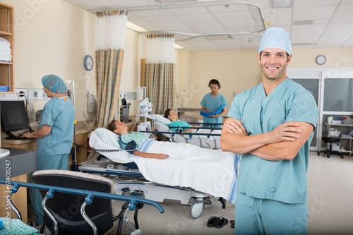 Nurse With Colleagues And Patient's In Hospital Ward