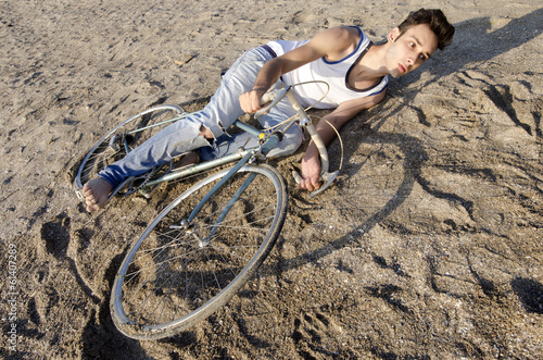 Man riding a bycicle on a sand, guy falling with his bike