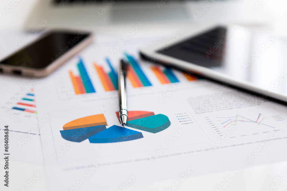 Financial charts on the table with tablet phone and pen Financial charts on the table with tablet phone and pen