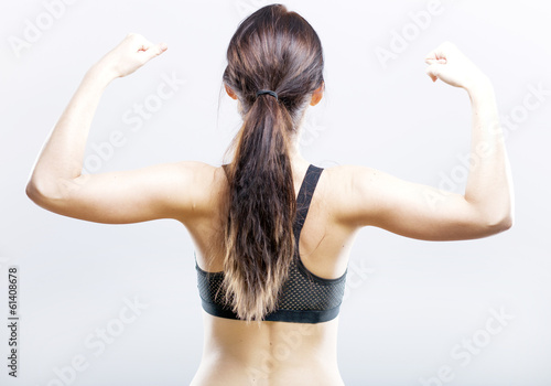 Canvas Print Fit woman flexing her biceps, rear view